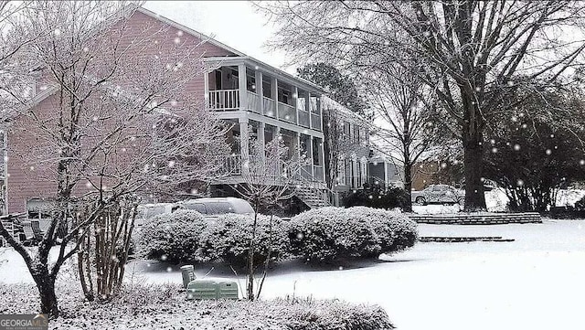 snow covered property with stairway