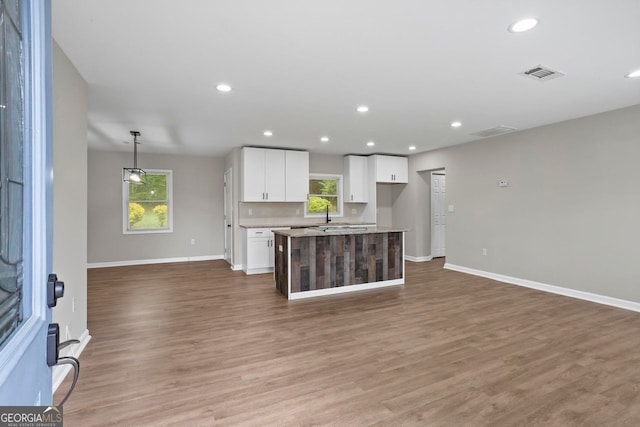 unfurnished living room featuring baseboards, recessed lighting, wood finished floors, and visible vents