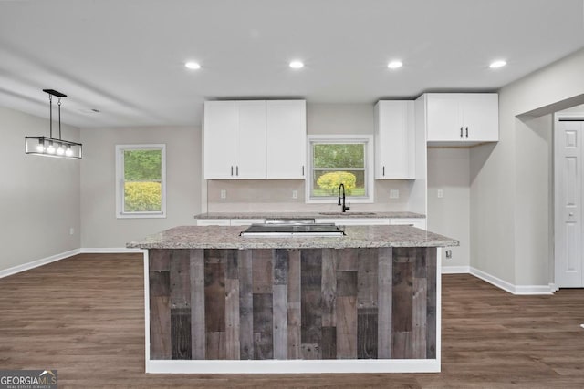 kitchen featuring baseboards, a sink, white cabinetry, and a kitchen island