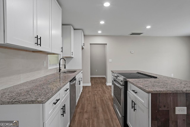 kitchen featuring dark wood-style floors, a center island, white cabinetry, a sink, and stainless steel appliances