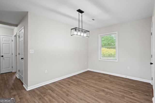 unfurnished dining area with baseboards, wood finished floors, and visible vents