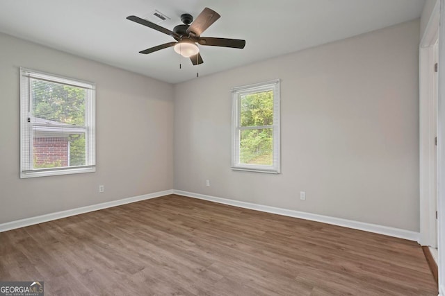 spare room featuring baseboards, ceiling fan, wood finished floors, and visible vents