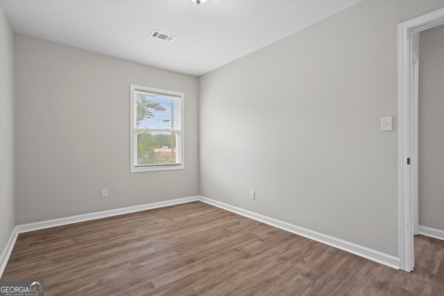 spare room featuring baseboards, visible vents, and wood finished floors
