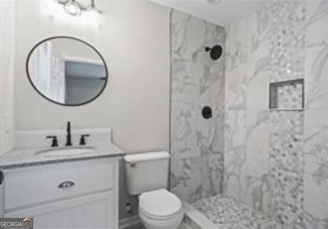 bathroom featuring vanity, a marble finish shower, and toilet