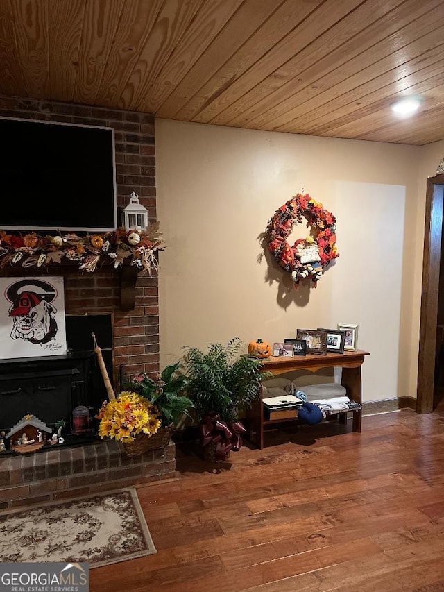 interior space with wooden ceiling, a brick fireplace, and wood finished floors