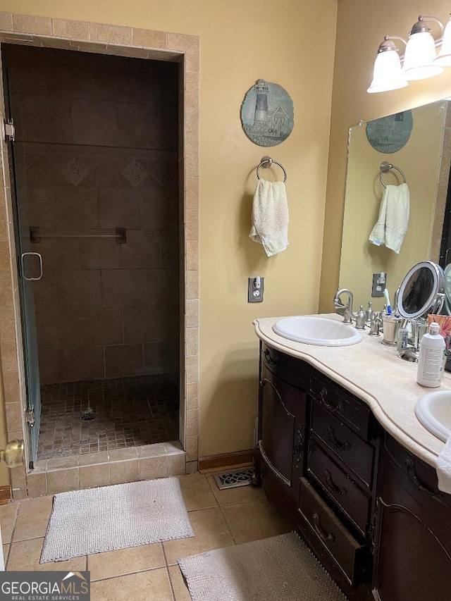 bathroom featuring double vanity, baseboards, tile patterned floors, a shower stall, and a sink