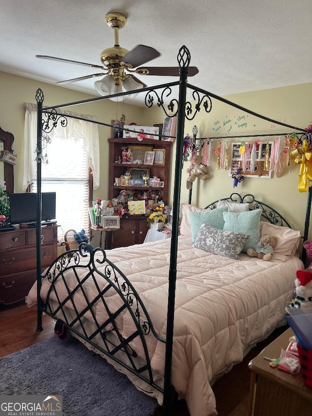 bedroom with a ceiling fan, vaulted ceiling, a textured ceiling, and wood finished floors