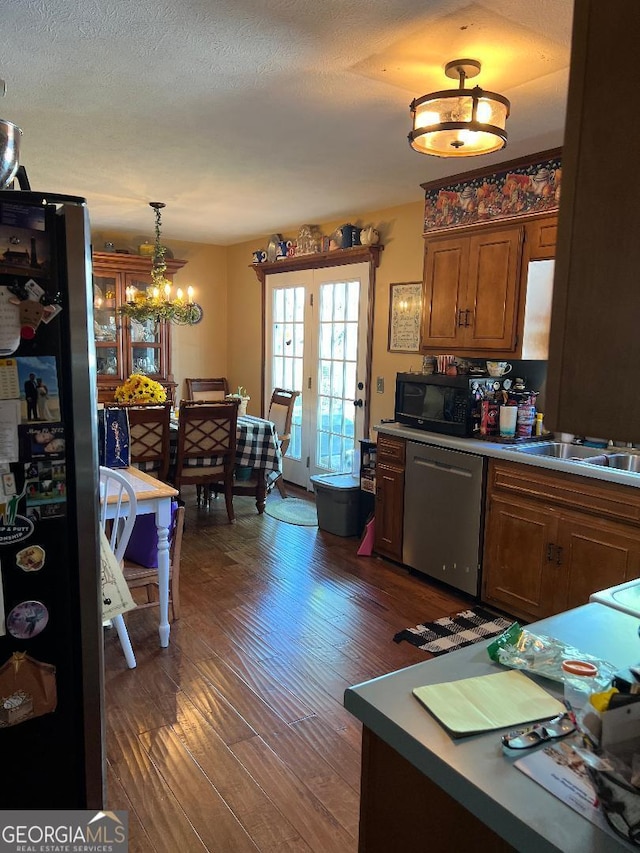 kitchen with a textured ceiling, stainless steel appliances, dark wood-type flooring, and pendant lighting