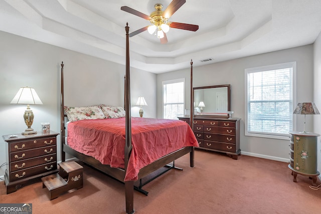 bedroom featuring a ceiling fan, visible vents, baseboards, carpet, and a raised ceiling