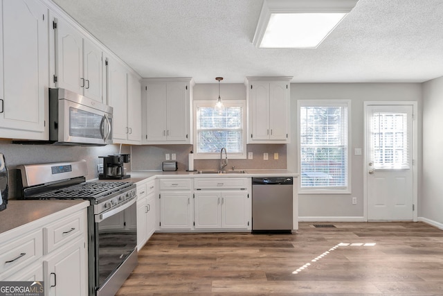 kitchen featuring stainless steel appliances, light wood-style floors, white cabinetry, and a sink