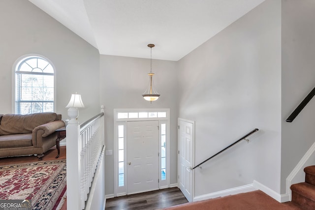 foyer entrance with high vaulted ceiling, stairs, baseboards, and dark wood-style flooring