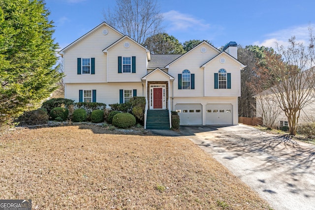 tri-level home with a garage, concrete driveway, and a chimney