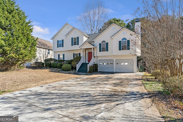 tri-level home featuring concrete driveway, a chimney, and an attached garage