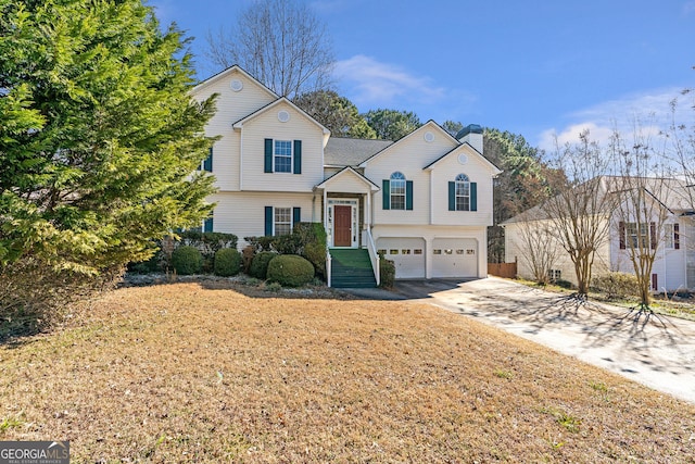 tri-level home with a garage, concrete driveway, and a chimney