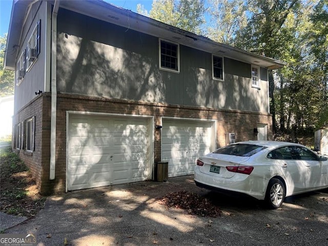 view of property exterior featuring an attached garage, driveway, and brick siding