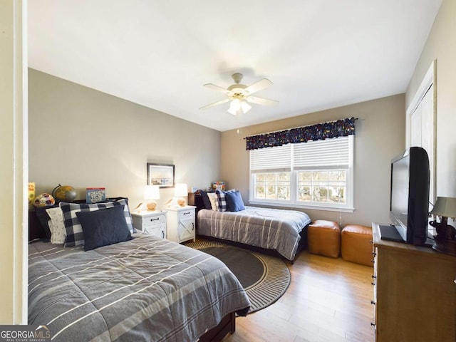 bedroom with light wood-style floors, ceiling fan, and a closet