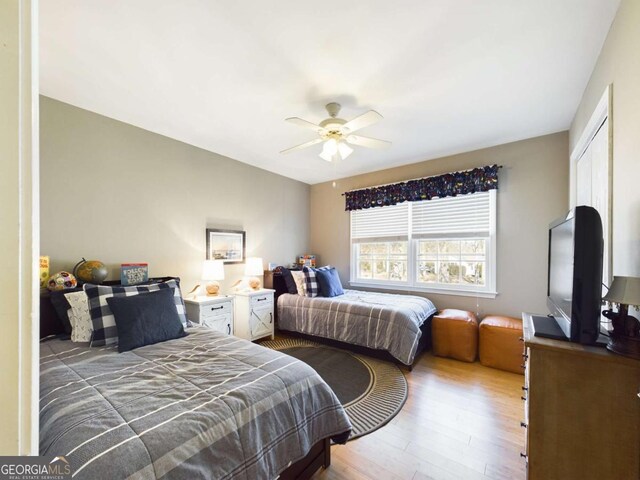bedroom with light wood-type flooring, a ceiling fan, and a closet