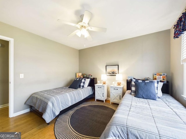 bedroom with a ceiling fan, baseboards, and light wood-style flooring