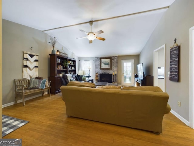 living room with a ceiling fan, a brick fireplace, baseboards, light wood finished floors, and lofted ceiling