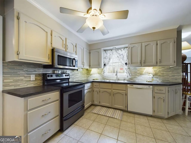 kitchen featuring appliances with stainless steel finishes, dark countertops, a sink, and crown molding