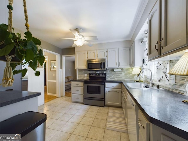 kitchen with dark countertops, backsplash, stainless steel appliances, and a sink