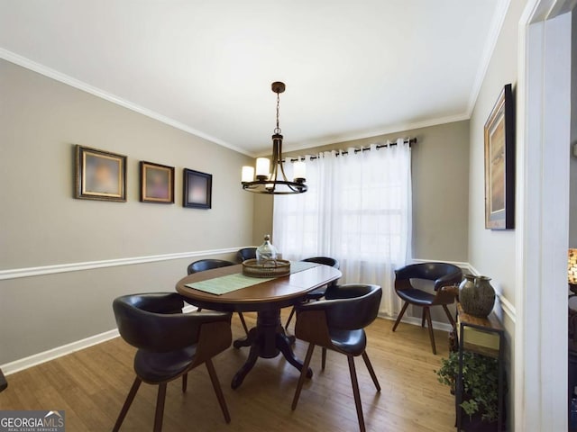 dining space featuring light wood-style floors, ornamental molding, baseboards, and an inviting chandelier