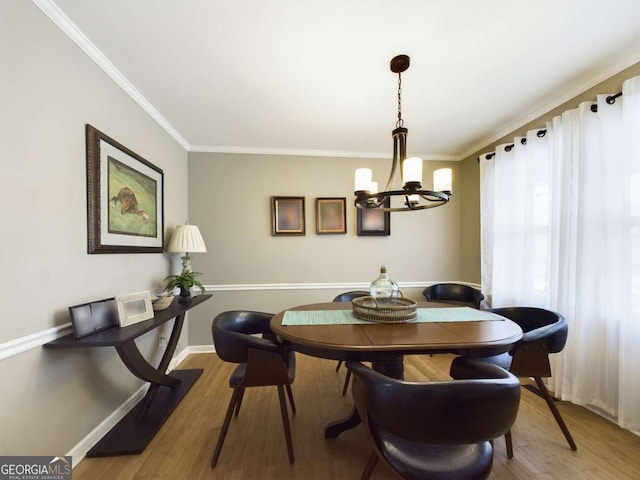 dining area featuring a chandelier, crown molding, baseboards, and wood finished floors