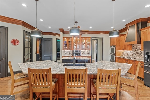 kitchen with stainless steel appliances, recessed lighting, a spacious island, glass insert cabinets, and wall chimney exhaust hood