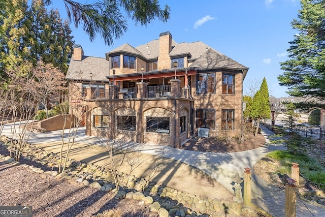 rear view of house featuring a patio, a chimney, central AC unit, fence, and a balcony