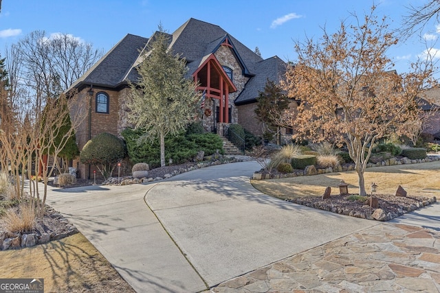 view of front of house featuring driveway, stone siding, and brick siding