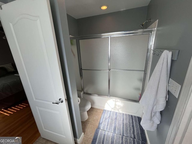 bathroom featuring shower / bath combination with glass door, tile patterned flooring, and toilet