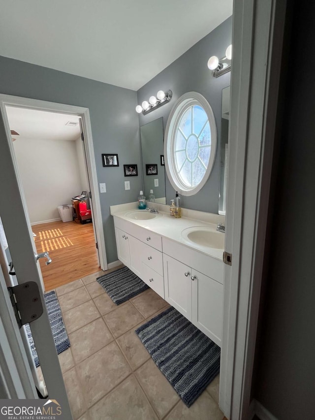 bathroom featuring baseboards, double vanity, a sink, and tile patterned floors