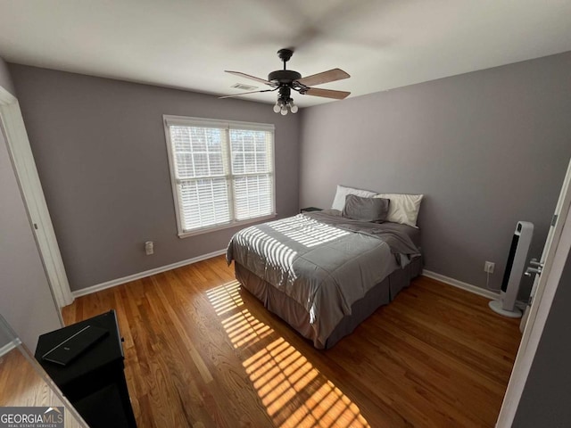 bedroom with visible vents, ceiling fan, baseboards, and wood finished floors