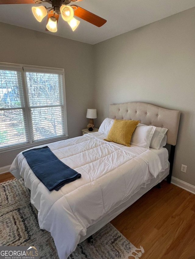 bedroom with a ceiling fan, baseboards, and wood finished floors