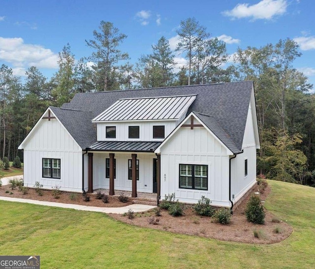 modern farmhouse featuring a standing seam roof, covered porch, board and batten siding, and a front yard