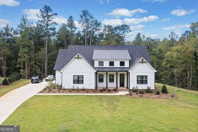 modern farmhouse style home with metal roof, covered porch, concrete driveway, a standing seam roof, and a front yard