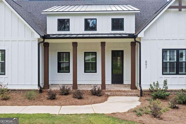 entrance to property with metal roof, roof with shingles, a standing seam roof, a porch, and board and batten siding