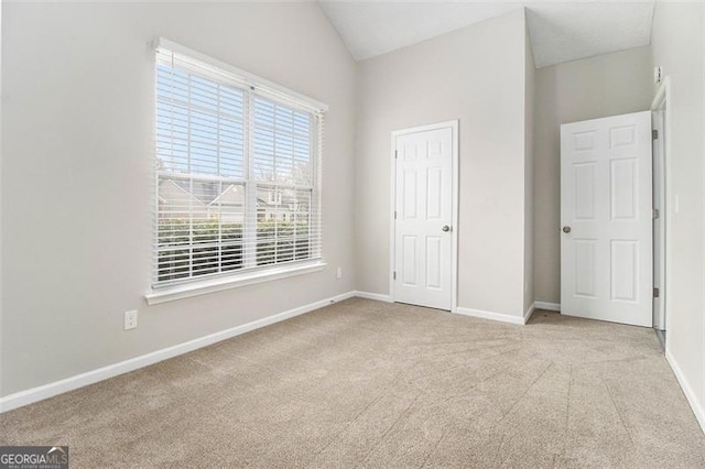 unfurnished bedroom with carpet floors, baseboards, and vaulted ceiling