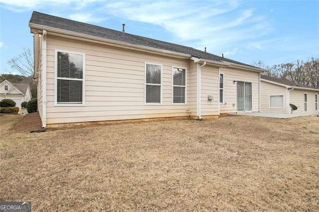 rear view of house featuring a lawn and a patio