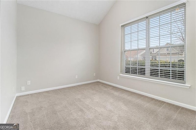 carpeted spare room with vaulted ceiling and baseboards