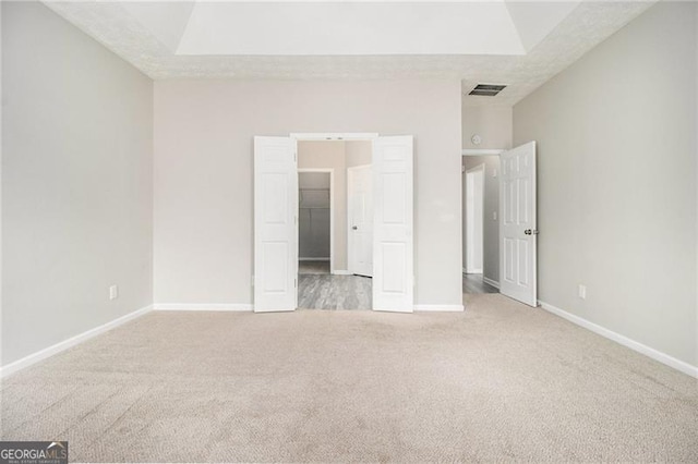 unfurnished bedroom with carpet floors, a walk in closet, visible vents, and baseboards