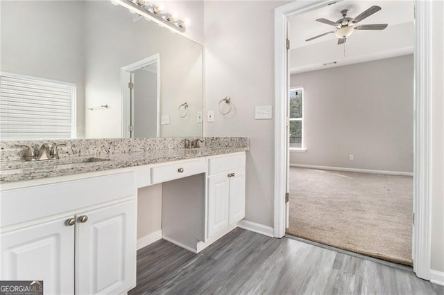 full bath featuring ceiling fan, wood finished floors, a sink, baseboards, and double vanity