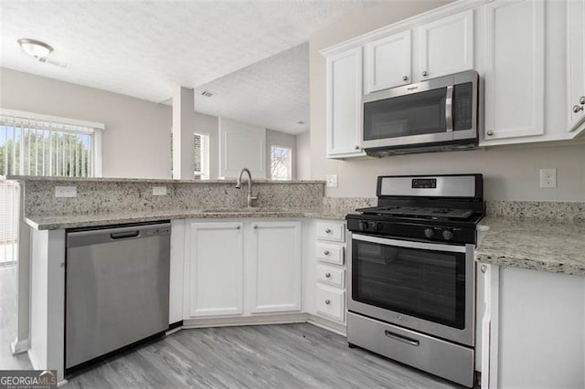 kitchen featuring stainless steel appliances, white cabinets, a sink, and a textured ceiling