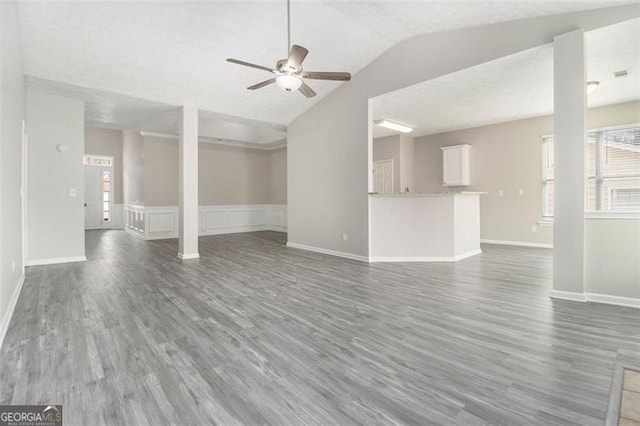 unfurnished living room featuring ceiling fan, vaulted ceiling, wood finished floors, and baseboards