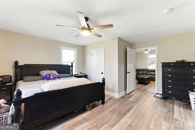 bedroom featuring light wood-style flooring, multiple windows, baseboards, and ceiling fan