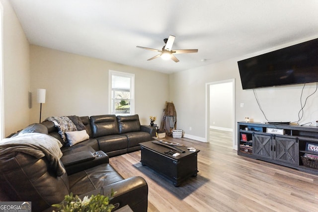 living room with ceiling fan, baseboards, and wood finished floors