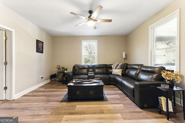 living room featuring ceiling fan, light wood finished floors, and baseboards