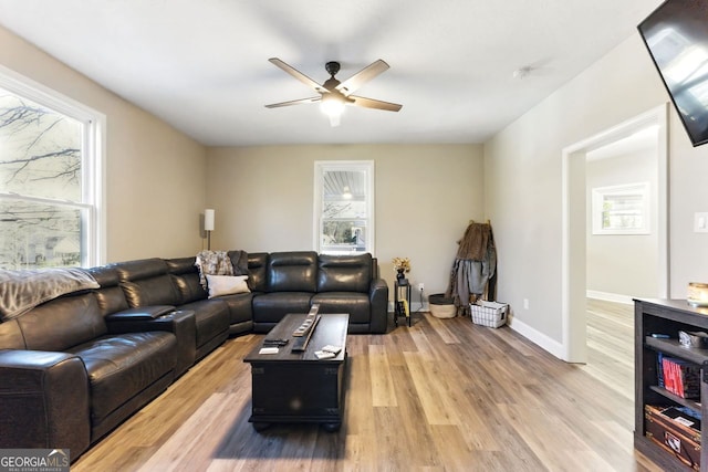 living room featuring light wood-type flooring, ceiling fan, and baseboards