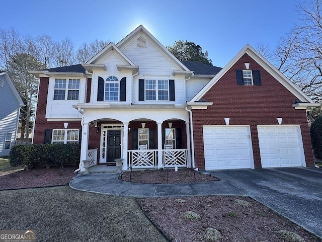 traditional-style home with driveway, covered porch, a garage, and brick siding