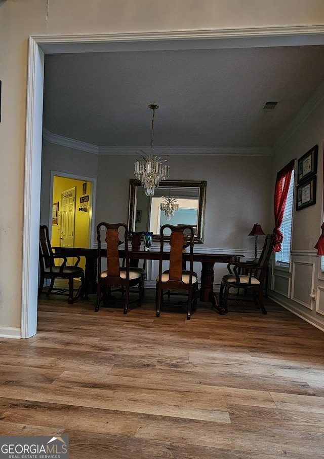 dining area featuring a chandelier, visible vents, ornamental molding, and wood finished floors